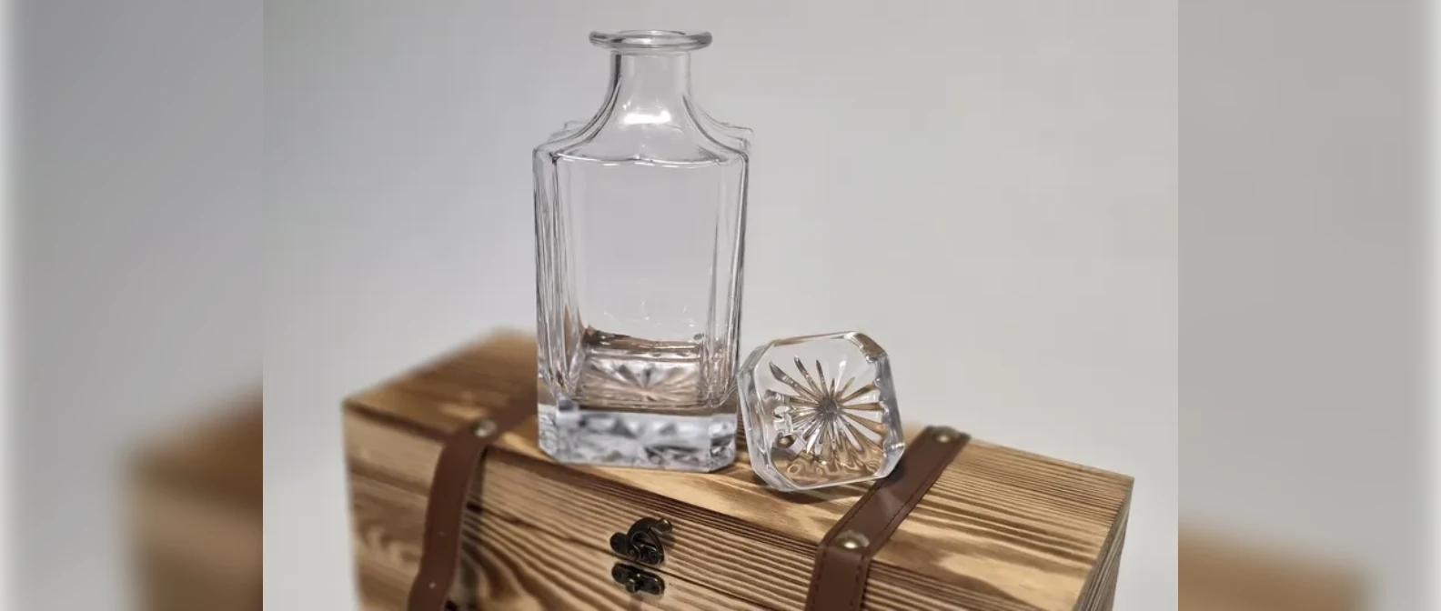 Square glass whiskey decanter with its stopper on a wooden box