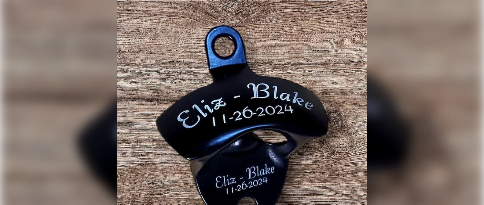 Personalized wall mounted bottle opener engraved with two names and a date, on a wood wall